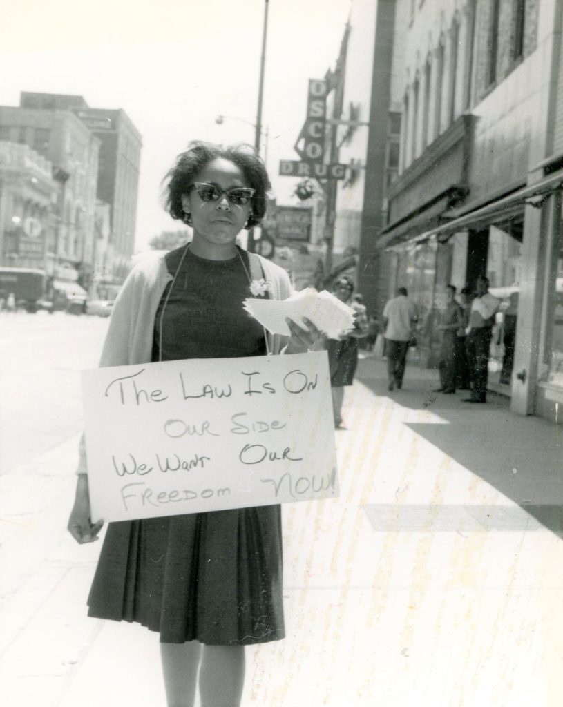 1963 A woman peacefully advocates for hiring of African Americans in downtown Joliet business