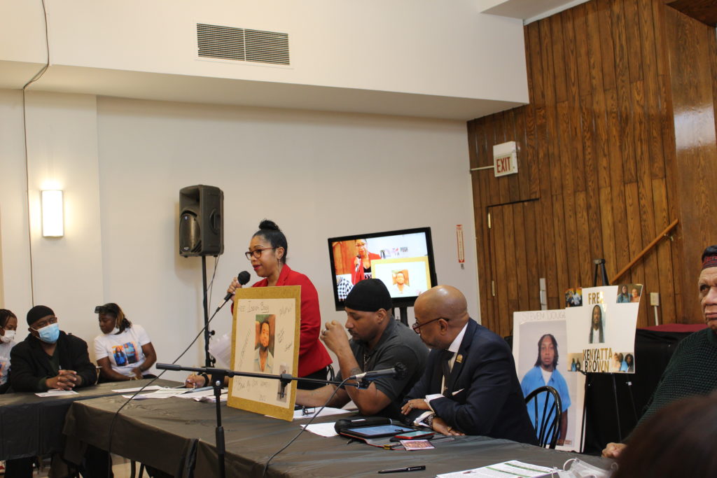 Darlisa Kendall mother of Isaiah holding a picture of him while speaking into a mic