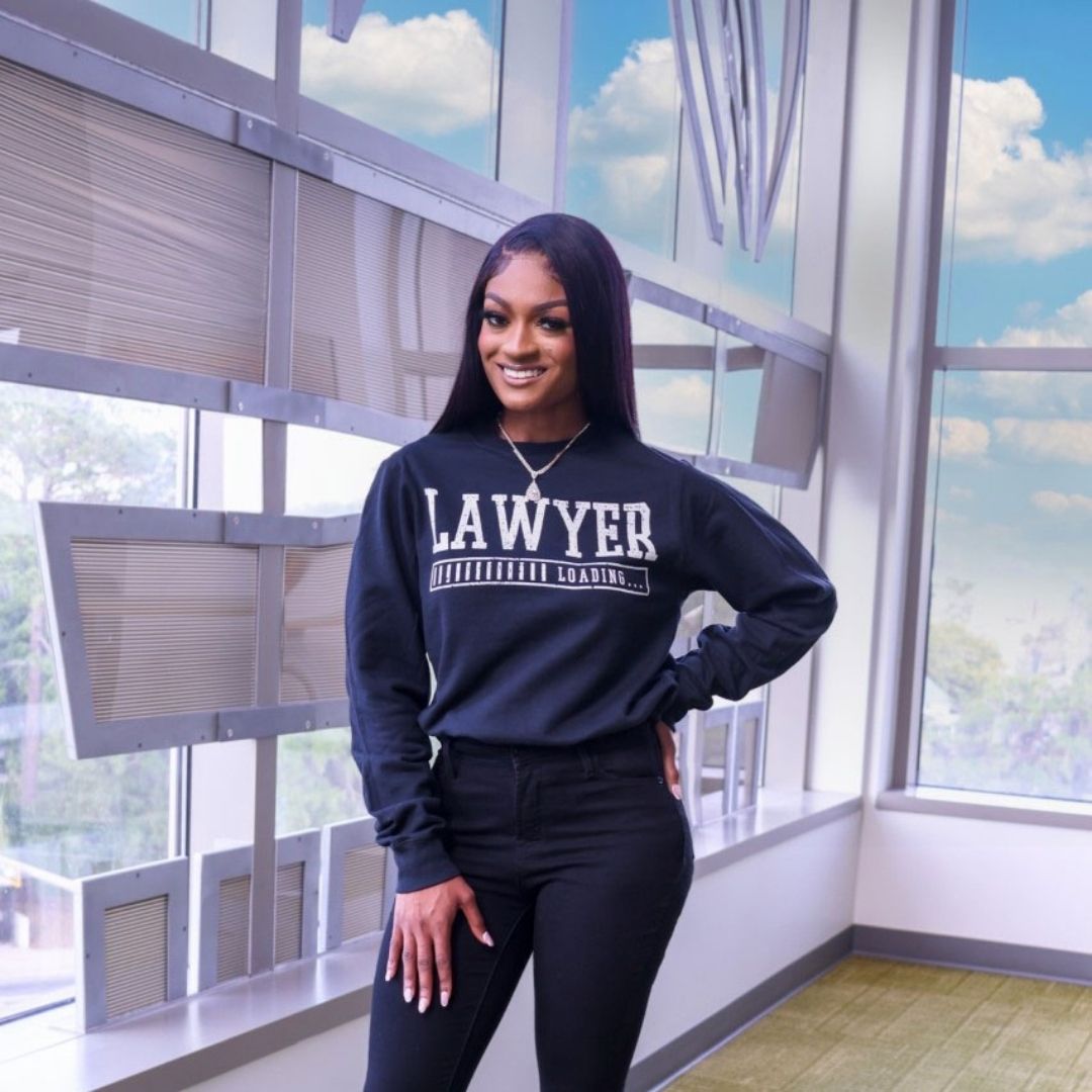 Nastassia-Janvier-standing-wearing-a-sweater-with-the-word-lawyer-on-it