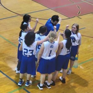 young girls basketball team standing in purple and white uniform