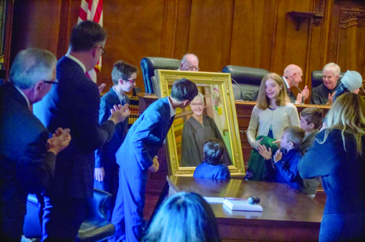THE GRANDCHILDREN OF Illinois Supreme Court Chief Justice Mary Jane Theis unveil her portrait Monday during the public ceremony for her being sworn in as chief justice. Theis is pictured seated in the Supreme Court chamber at the far right of the photo, sharing a laugh with Republican Justice Michael Burke. (Capitol News Illinois photo by Jerry Nowicki)