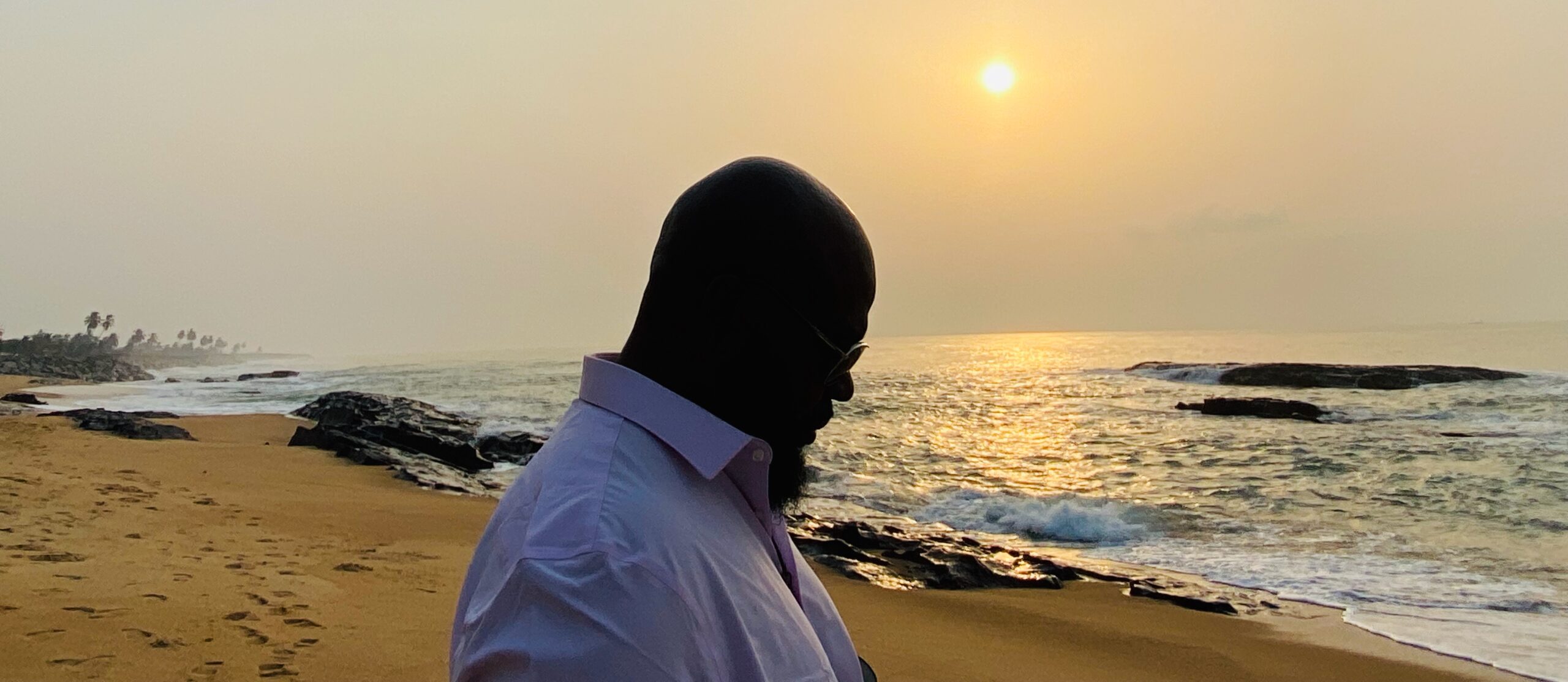 JOHN FOUNTAIN IN thought amid a setting sun off the coast of Ghana. (Photo: Monica Fountain)