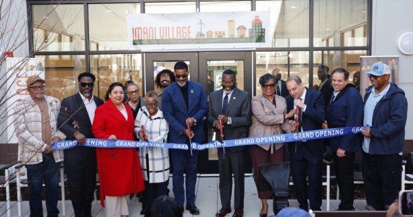 Mayor Brandon Johnson (center right, with scissors) joins Alderwoman Michelle Harris (center left, in red), Department of Housing Commissioner Lissette Castañeda (to the left of Alderwoman Harris), and Rev. Dr. Otis Moss III (center, with scissors and blue turtleneck) for the ribbon cutting ceremony of the newly completed Imani Village Senior Residence in the Pullman neighborhood. (Photo courtesy City of Chicago)